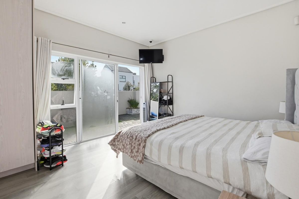 Bright bedroom featuring laminate flooring, built-in wardrobe, and a sliding glass door providing direct access to the outdoor patio area.