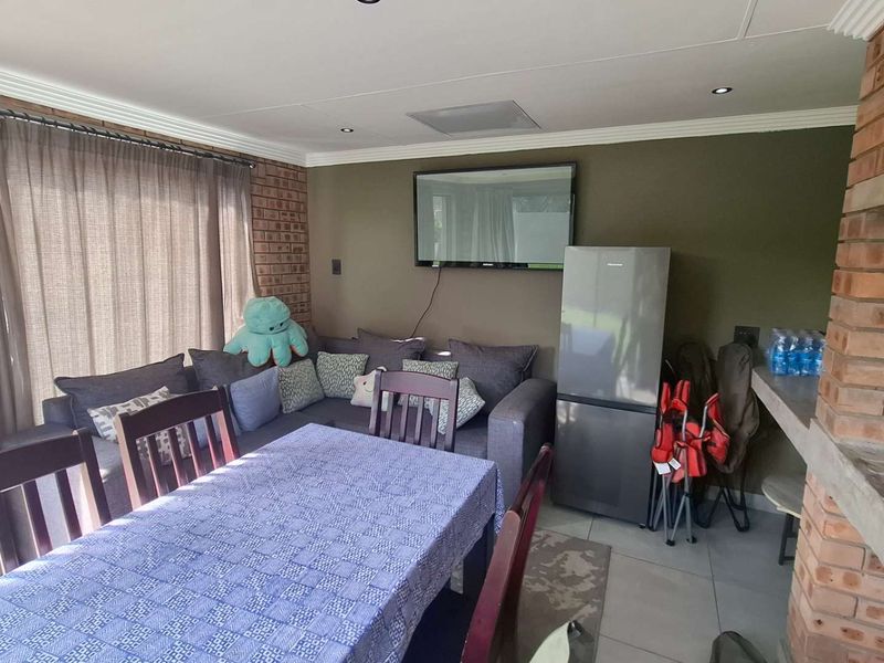 Covered patio area featuring a built-in brick braai, tiled flooring, and recessed lighting, providing a functional space for outdoor dining and relaxation.