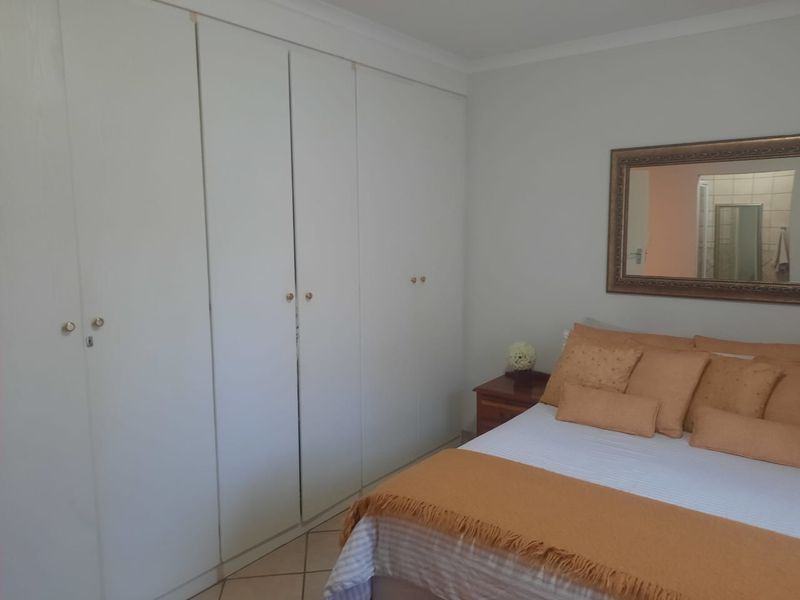 A bedroom featuring built-in cupboards and tiled flooring, offering a functional and neutral space.
