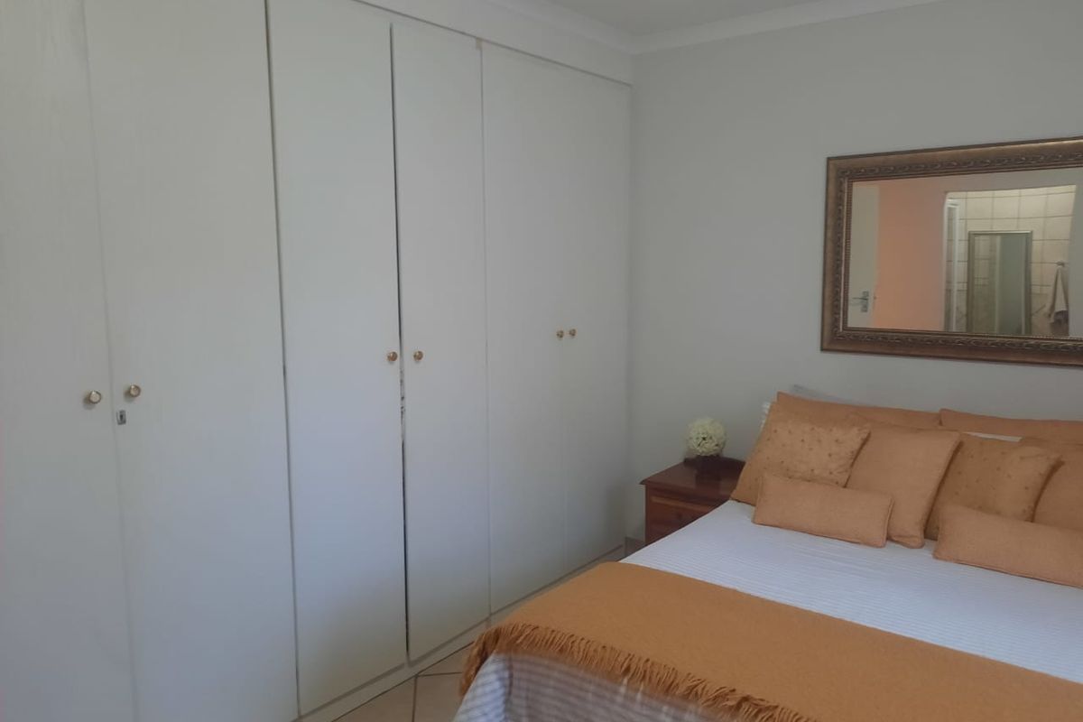 A bedroom featuring built-in cupboards and tiled flooring, offering a functional and neutral space.