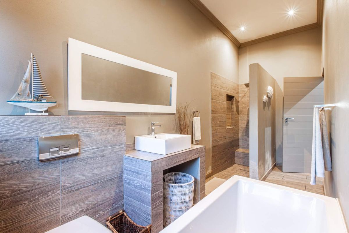 Modern bathroom featuring a vessel sink, wood-look tiled vanity, walk-in shower with recessed shelving, and a freestanding bathtub.