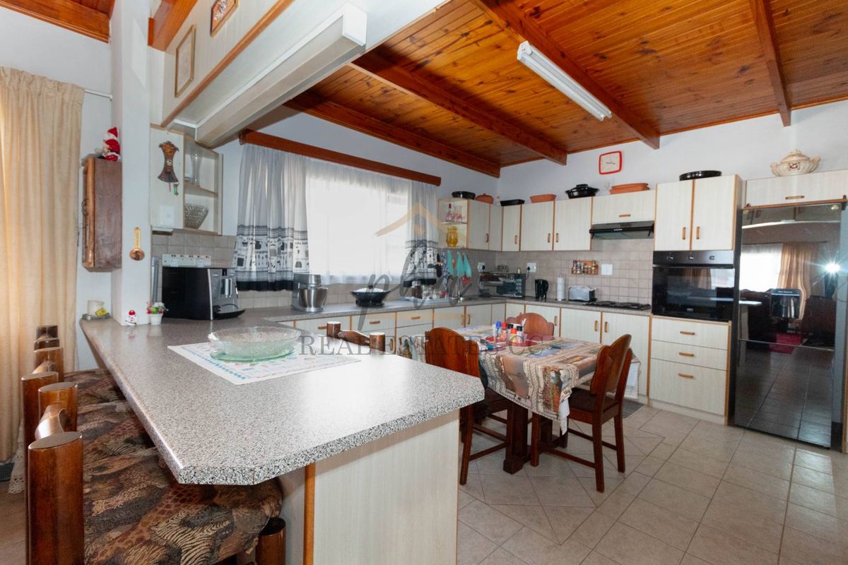 A functional kitchen featuring wooden beamed ceilings, built-in cabinetry, integrated oven, and a breakfast bar counter.