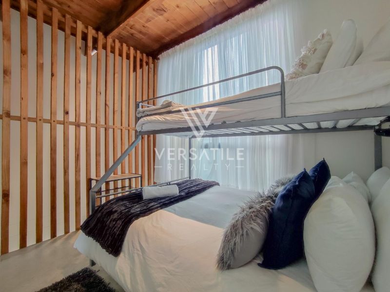 A cozy bedroom featuring an exposed timber ceiling and a decorative timber slat partition wall, creating a warm and textured aesthetic.