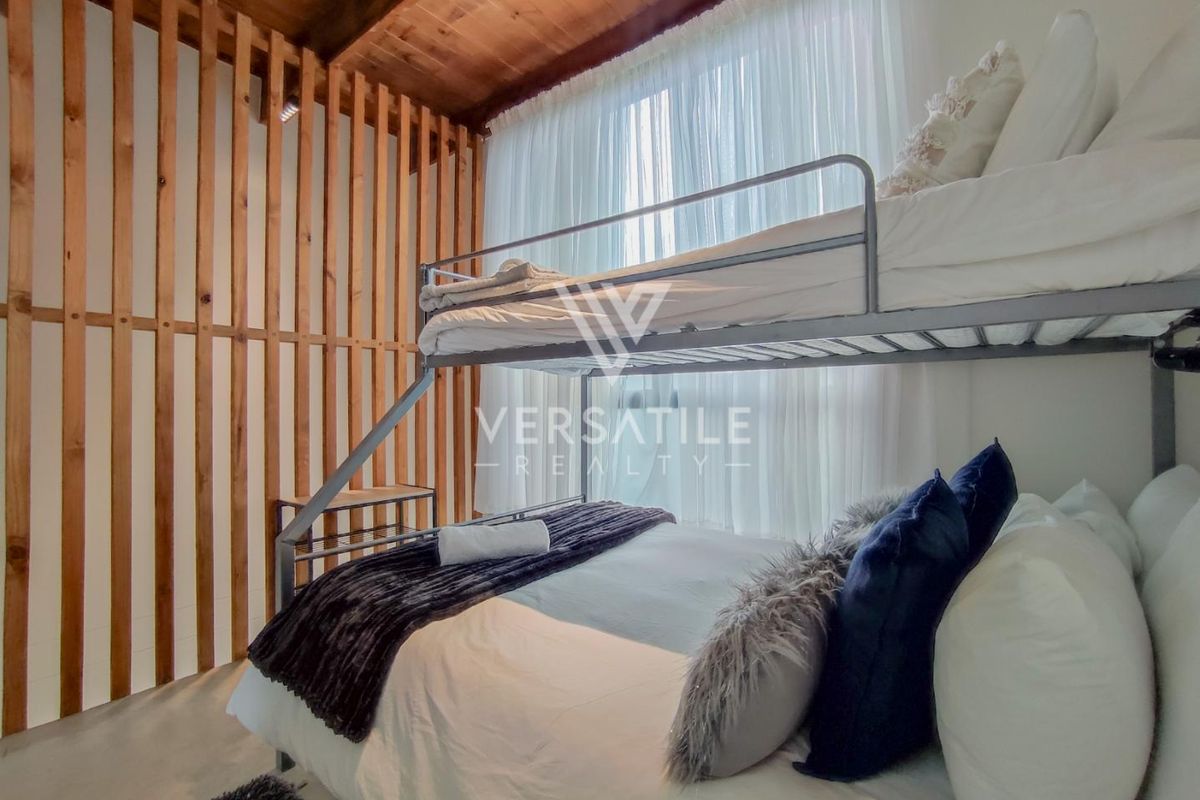 A cozy bedroom featuring an exposed timber ceiling and a decorative timber slat partition wall, creating a warm and textured aesthetic.