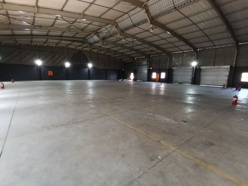 Spacious industrial warehouse featuring high-clearance steel portal frame construction, polished concrete flooring, and multiple roller shutter doors for efficient access.