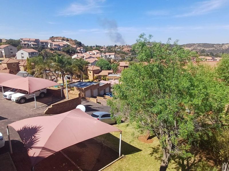 Elevated view overlooking a residential complex featuring paved parking areas with shade cloth carports and established garden surroundings.