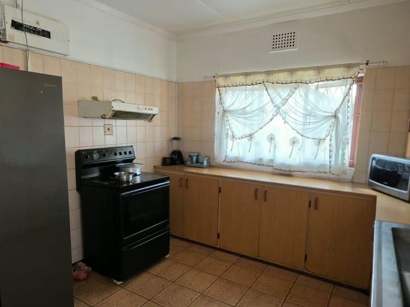 A dated kitchen featuring original wooden cabinetry, tiled splashbacks, and tiled flooring, offering significant potential for a modern renovation.
