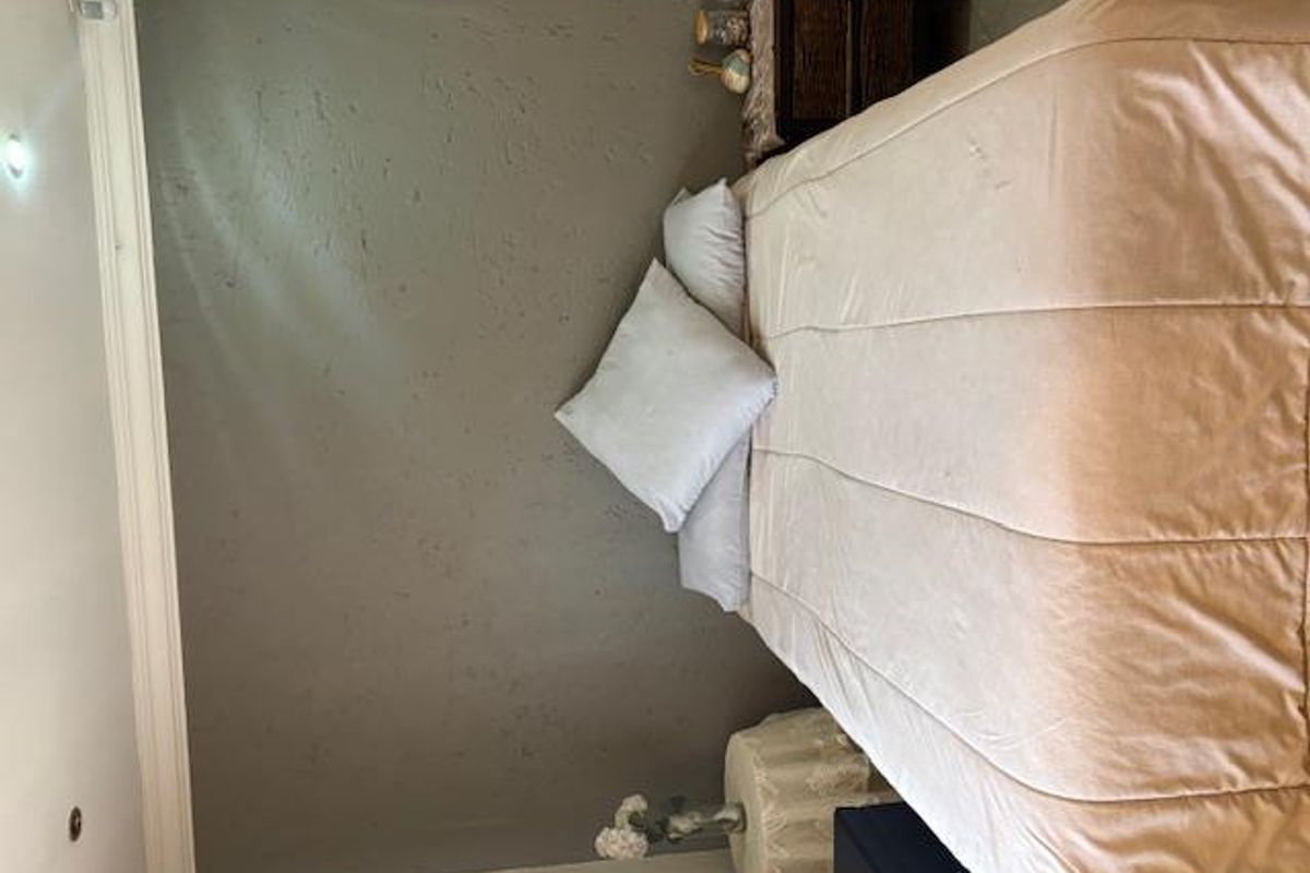 A bedroom featuring a textured accent wall, coving, and recessed ceiling lighting.