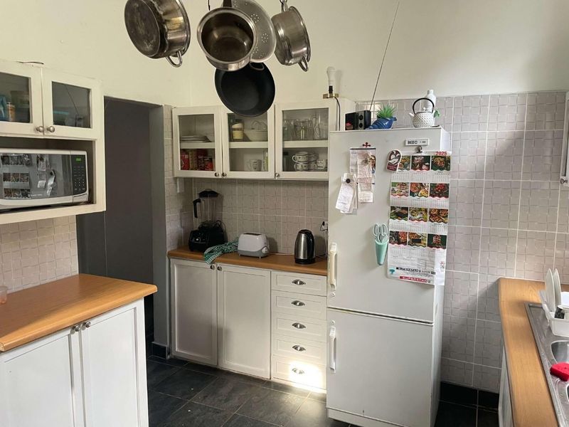 A functional kitchen featuring white cabinetry, laminate countertops, tiled backsplash, and built-in microwave, offering a practical layout for daily meal preparation.