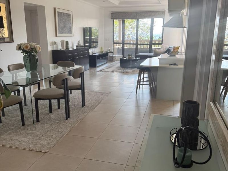 Spacious open-plan living and dining area featuring a modern kitchen island, tiled flooring, and large sliding doors leading to an outdoor space.