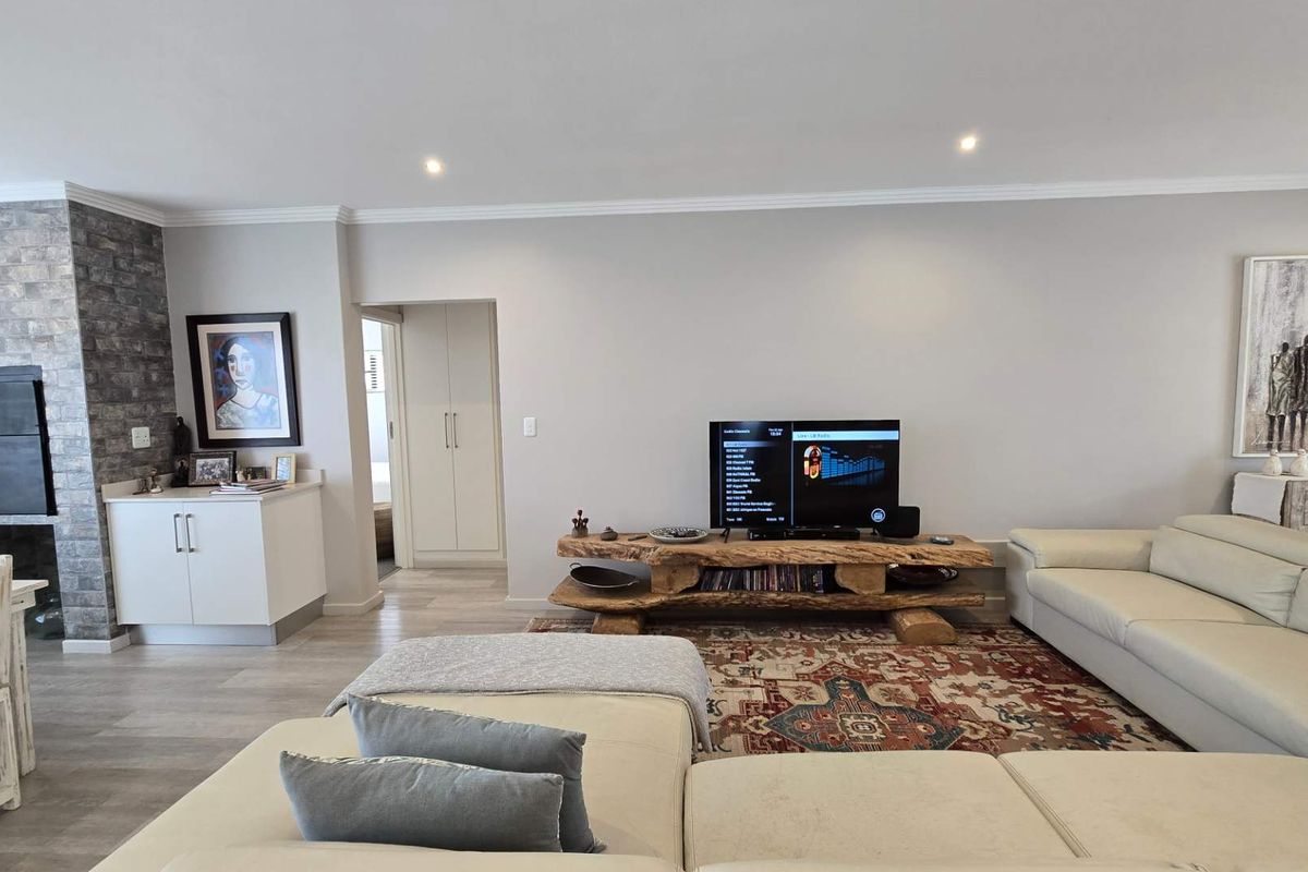 Spacious living area featuring a stone-clad fireplace, recessed downlighting, and neutral flooring, creating a comfortable and well-maintained environment.