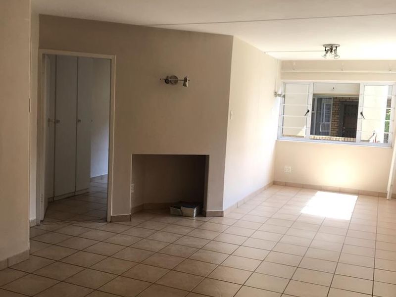 An empty, open-plan living area featuring tiled flooring, a built-in fireplace, and neutral walls, offering a blank canvas for interior design.