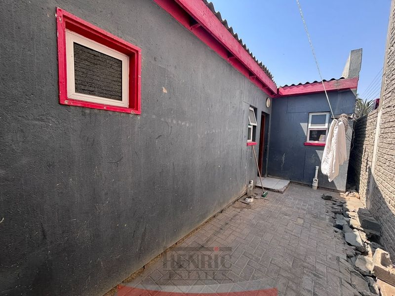 Rear exterior courtyard area featuring paved flooring and boundary walling, providing access to the rear of the townhouse.