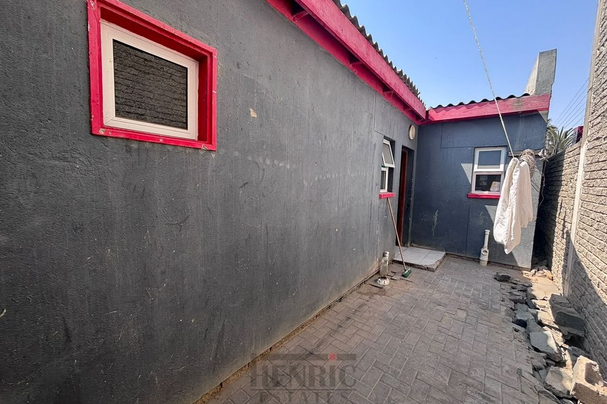 Rear exterior courtyard area featuring paved flooring and boundary walling, providing access to the rear of the townhouse.