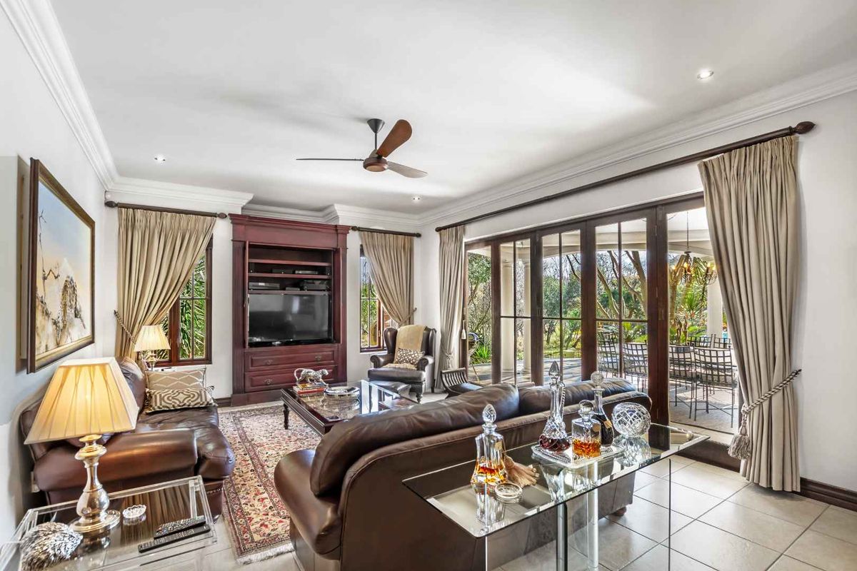 Spacious living room featuring built-in cabinetry, tiled flooring, and large glass sliding doors opening onto a covered patio area.