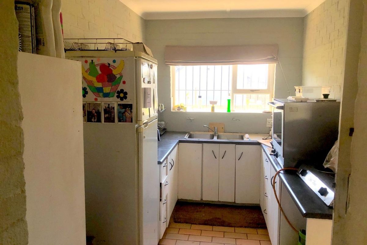 A compact kitchen featuring a double sink, laminate countertops, and basic cabinetry, with a window providing natural light.