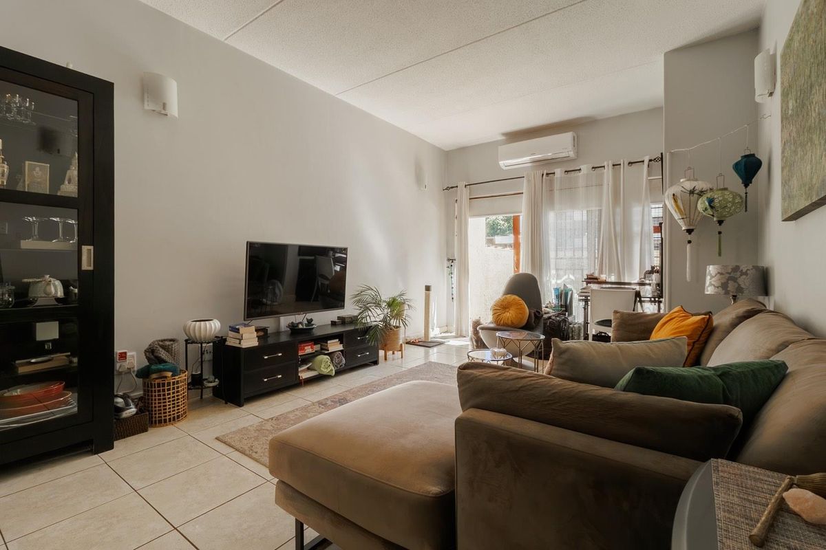 A comfortable living room featuring tiled flooring, wall-mounted air conditioning unit, and sliding glass doors providing access to the outdoor area.