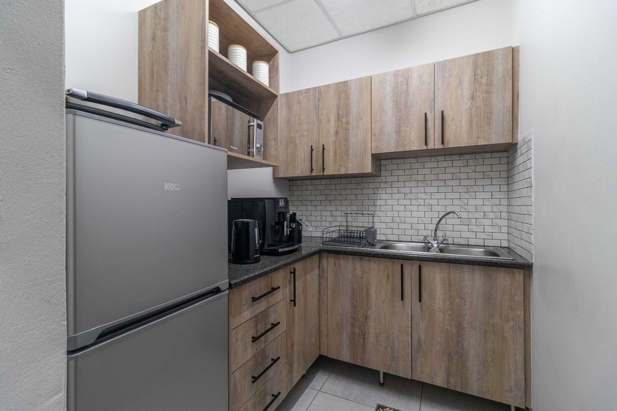 Compact kitchenette featuring wood-look cabinetry, granite countertops, a stainless steel sink, and a subway tile backsplash.