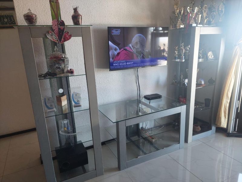 A living room area featuring tiled flooring and wall-mounted television setup.