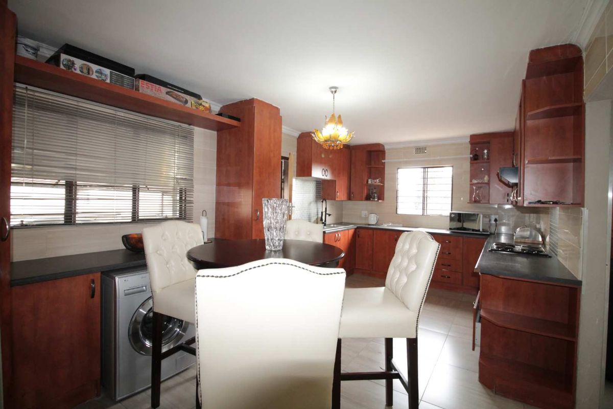 A functional kitchen featuring wood-finish cabinetry, dark countertops, integrated appliance space, and tiled flooring, offering a practical layout for daily meal preparation.