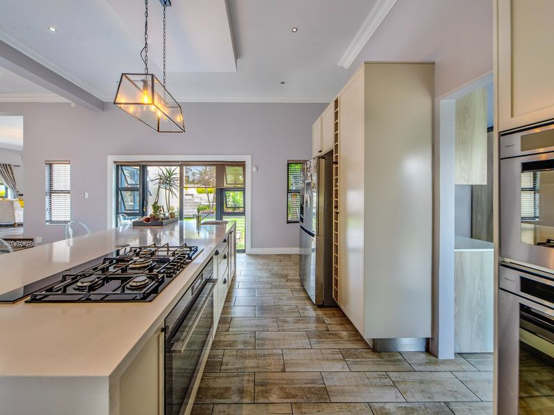 Modern kitchen featuring a large island with integrated gas cooktop, built-in oven, ample cabinetry, and direct access to the outdoor area.