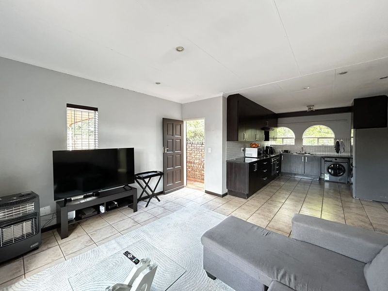 Open-plan living area featuring a kitchen with dark cabinetry, granite countertops, and tiled flooring, leading directly to an exterior entrance.