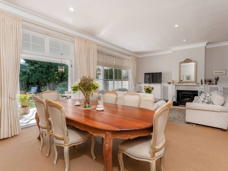 Spacious open-plan living and dining area featuring a fireplace, built-in cabinetry, and large french doors opening to the garden.