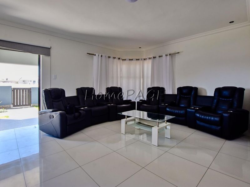 Spacious living room featuring large format floor tiles, recessed lighting, and direct access to an outdoor patio area through a sliding glass door.