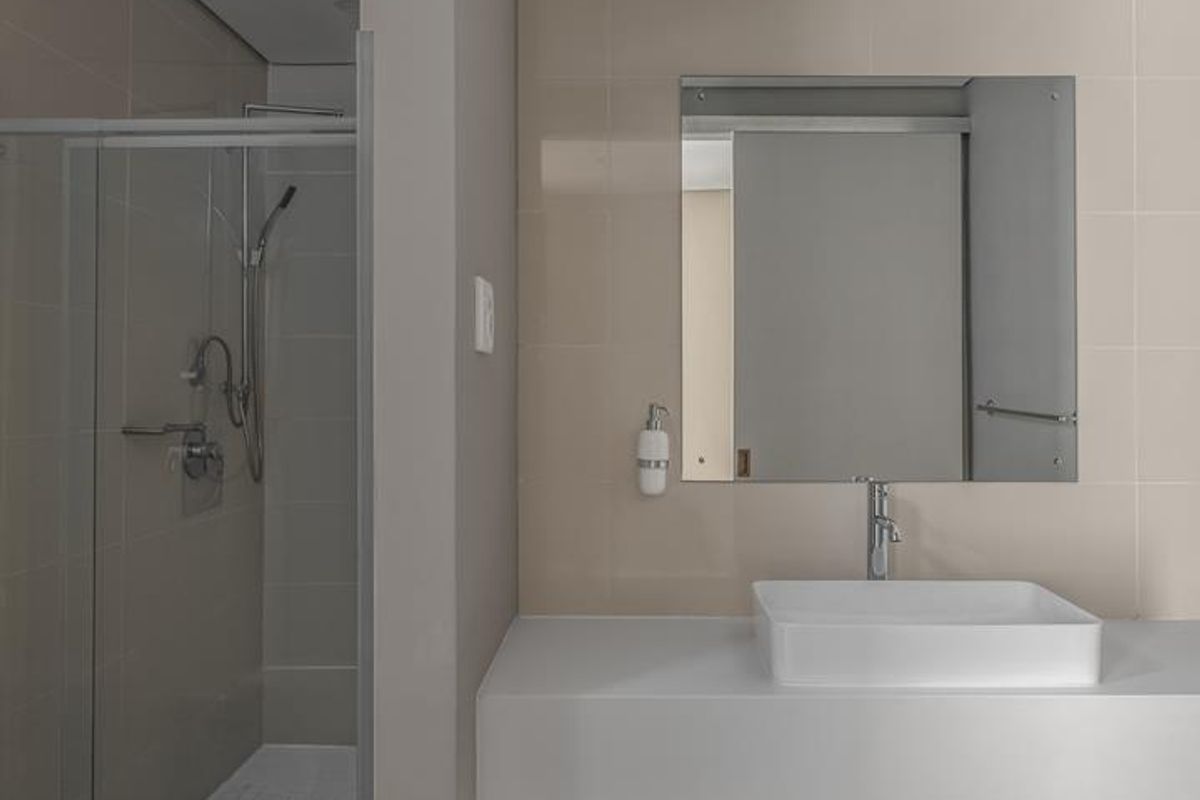 Modern bathroom featuring a floating vanity with a vessel sink, a frameless glass shower enclosure, and neutral wall tiling.