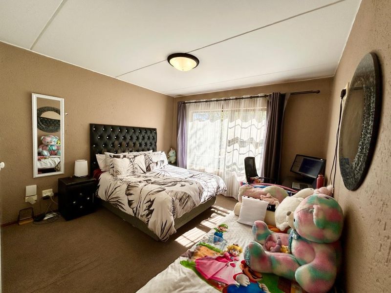 A bedroom featuring carpeted flooring, textured walls, a flush mount ceiling light, and a sliding glass door providing natural light.