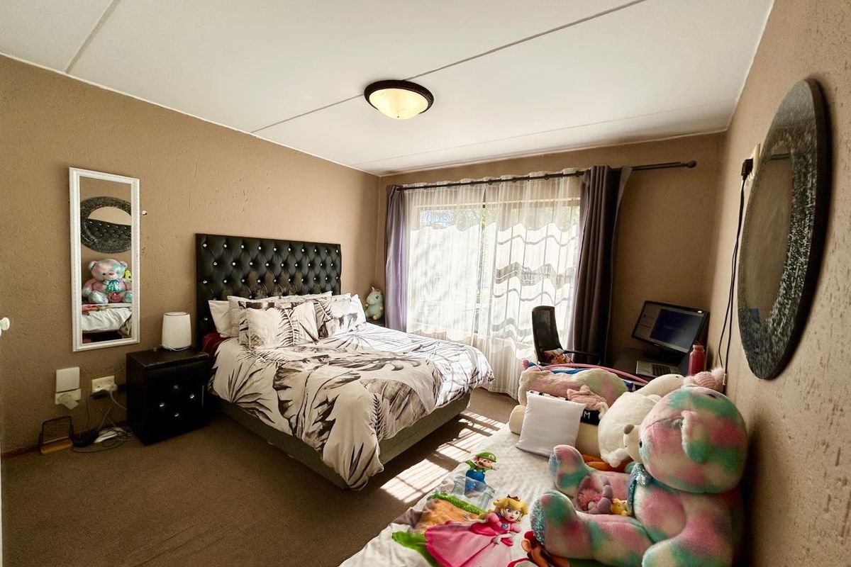 A bedroom featuring carpeted flooring, textured walls, a flush mount ceiling light, and a sliding glass door providing natural light.
