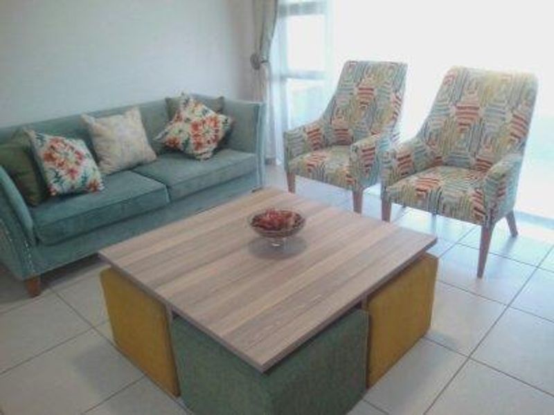 A bright living room area featuring neutral tiled flooring and a large sliding glass door providing natural light.