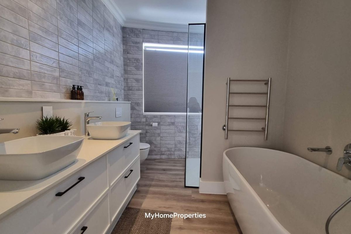 Modern bathroom featuring a double vanity with vessel sinks, a freestanding bathtub, a heated towel rail, and a walk-in shower with stylish tiled finishes.