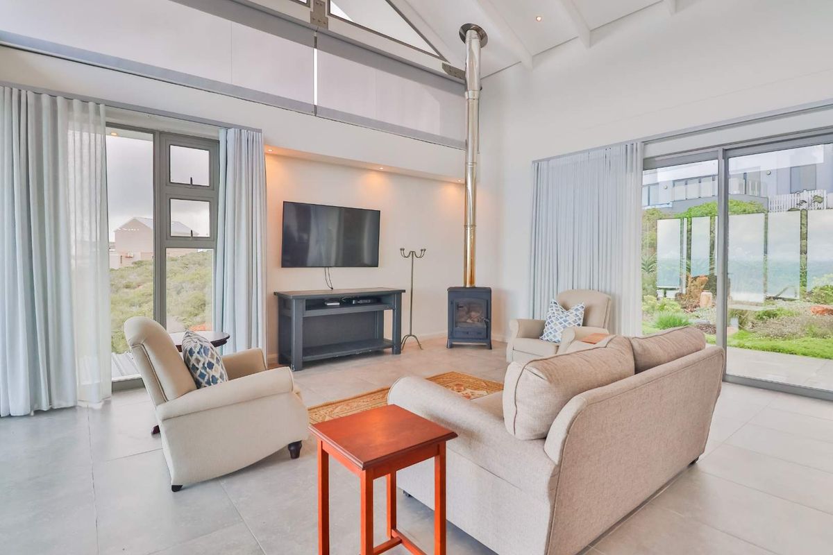Spacious living room featuring high vaulted ceilings, large glass sliding doors, and a modern freestanding fireplace, offering seamless indoor-outdoor flow.