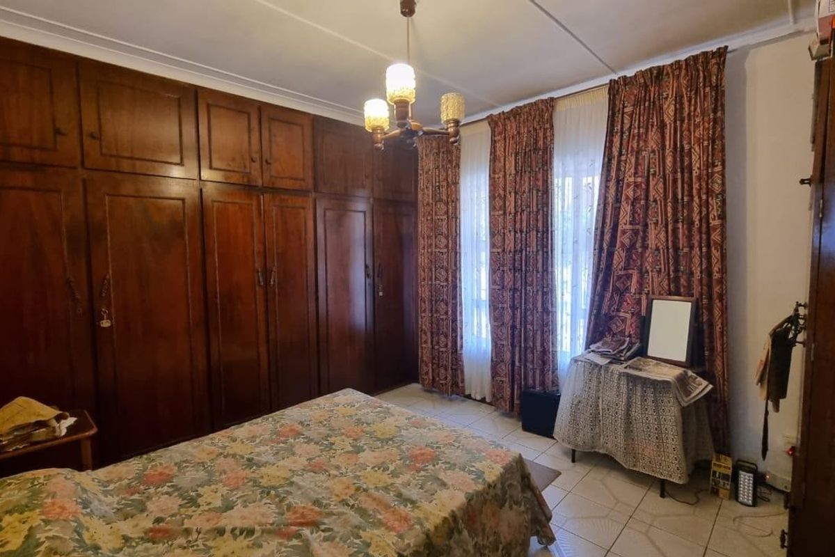A bedroom featuring extensive built-in wooden cabinetry, tiled flooring, and large windows with curtains, offering ample storage space.