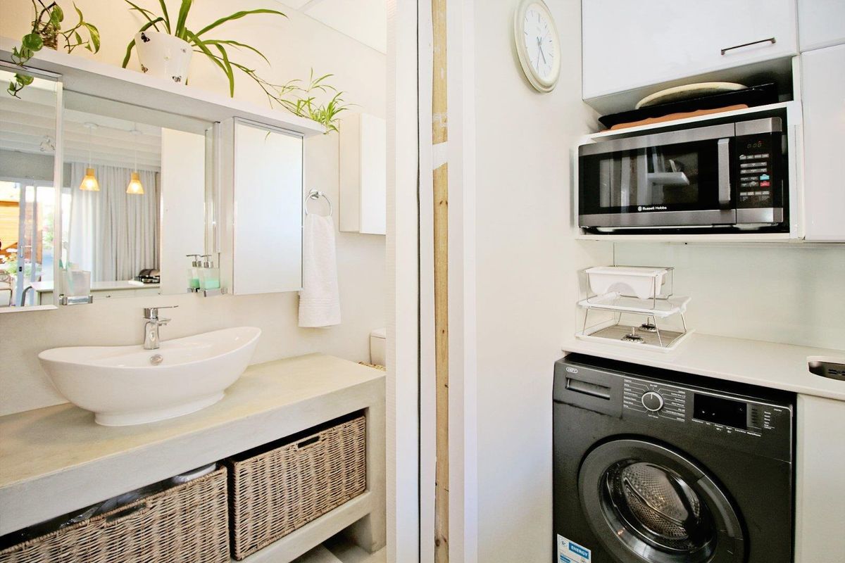 A combined bathroom and laundry area featuring a modern vessel sink vanity and built-in laundry cabinetry with integrated appliance space.