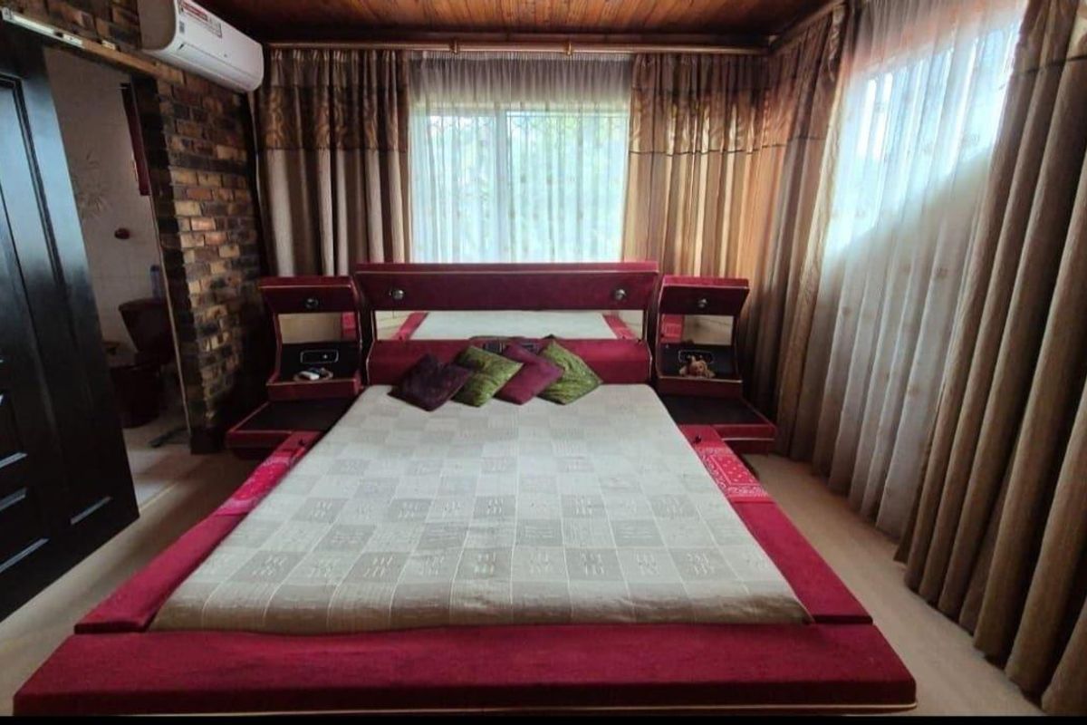 A bedroom featuring a timber ceiling, exposed brick accent wall, and a wall-mounted air conditioning unit.