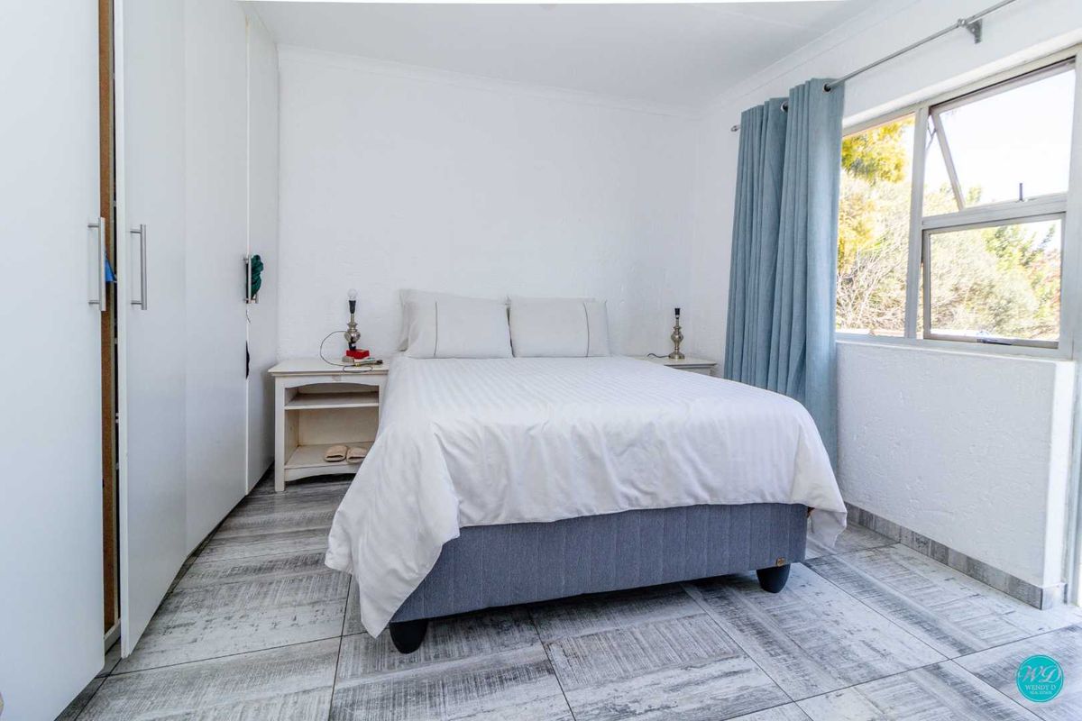 A bright bedroom featuring built-in cupboards, tiled flooring, and a window with natural light.
