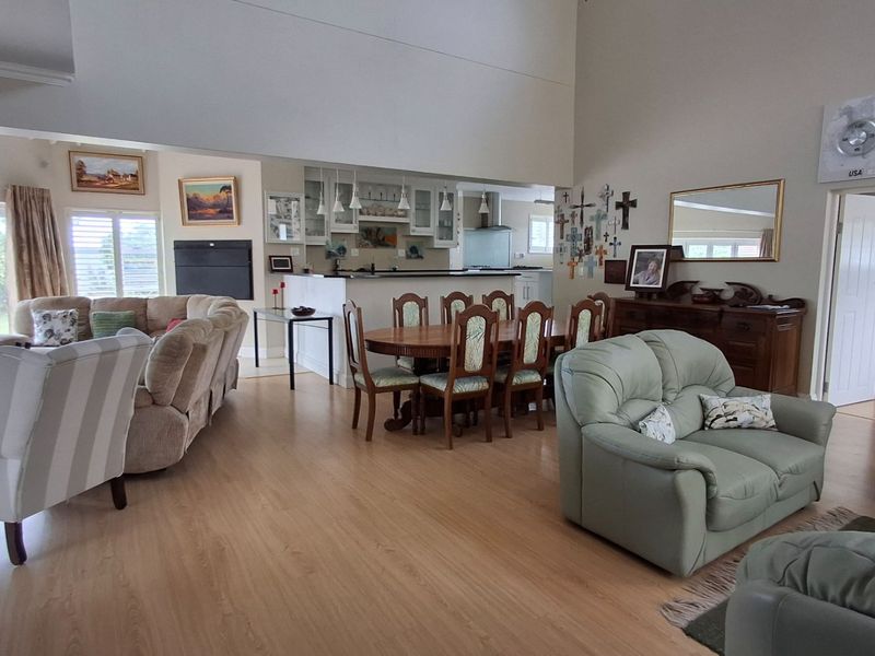 Spacious open-plan living and dining area featuring vaulted ceilings, laminate flooring, and a connected kitchen with built-in cabinetry and island.
