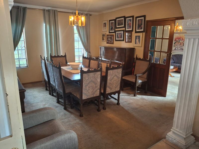 A traditional dining room featuring a timber-framed glass door, decorative column, and neutral wall finishes, offering a classic layout for formal dining.
