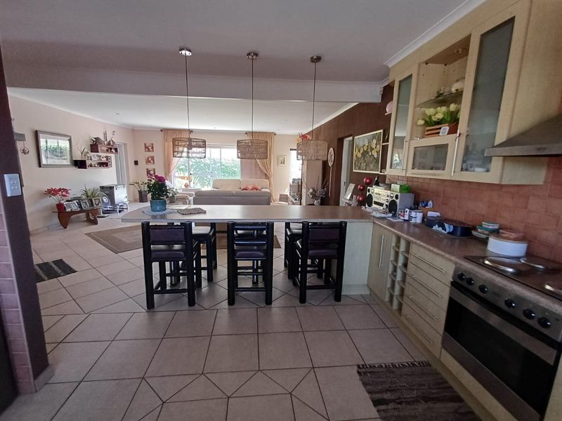 Spacious open-plan living area featuring a functional kitchen with built-in cabinetry, integrated appliances, and a central breakfast island flowing into the lounge.