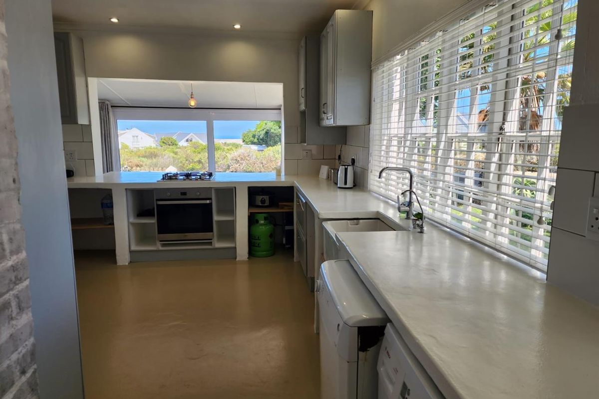 A functional kitchen featuring built-in cabinetry, a gas hob, an oven, and a large window with views, offering a bright and practical workspace.