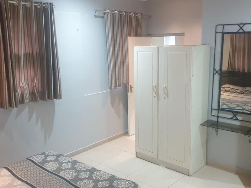 A functional bedroom featuring tiled flooring, recessed downlighting, and a built-in wardrobe, offering a neutral base for personalization.