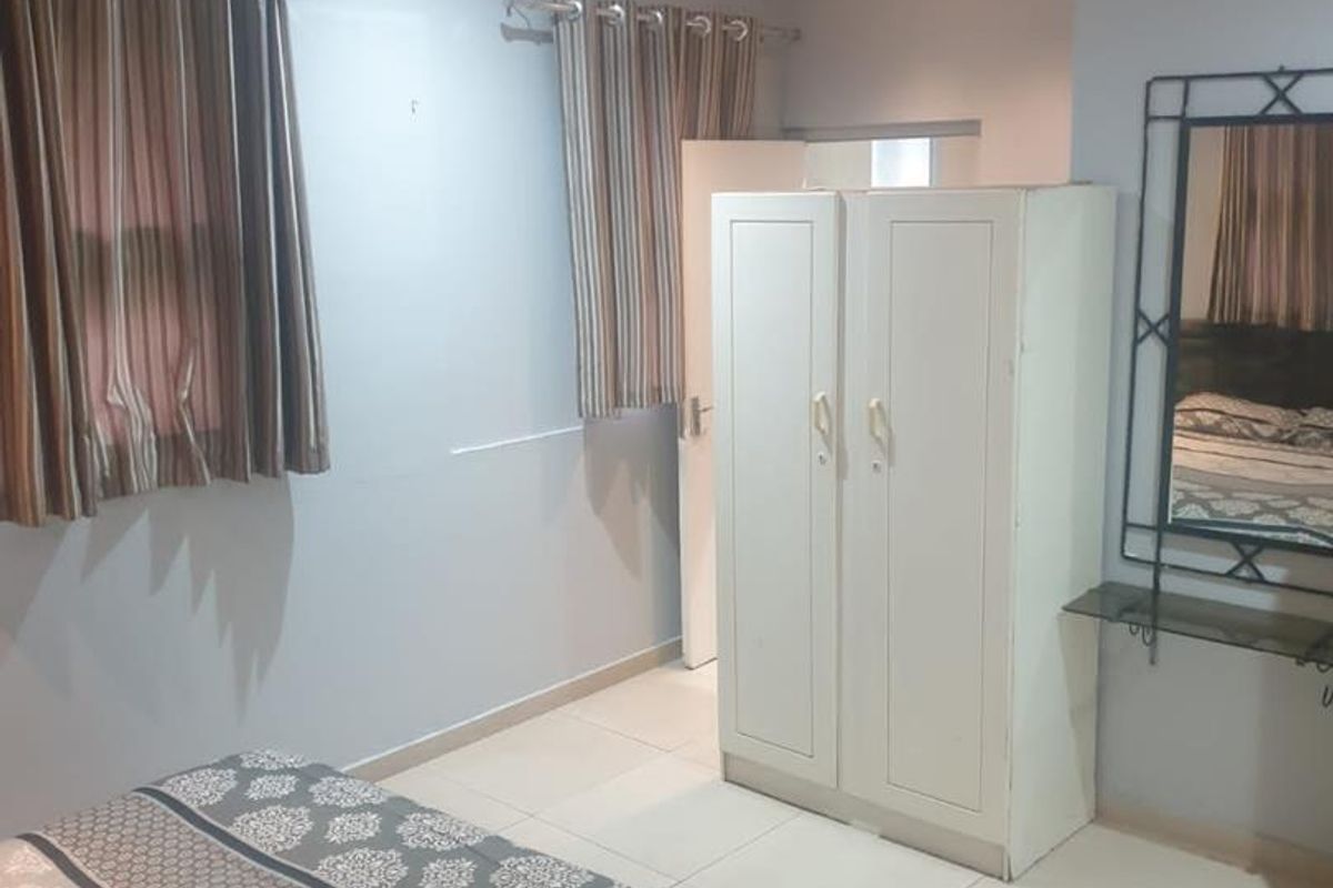 A functional bedroom featuring tiled flooring, recessed downlighting, and a built-in wardrobe, offering a neutral base for personalization.