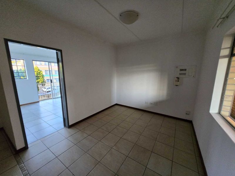 An empty, neutrally finished living area featuring tiled flooring, an intercom system, and an electrical distribution board, with access to an adjacent balcony.