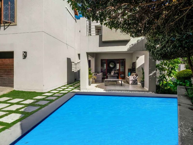 A well-maintained outdoor area featuring a swimming pool, a covered patio space, and a modern exterior facade with a garage.