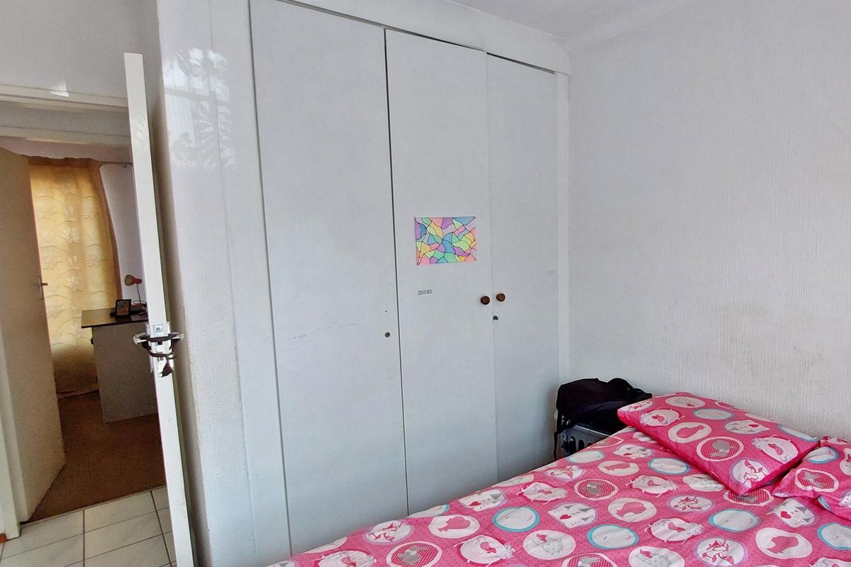 A bedroom featuring a built-in wardrobe with white doors and access to an adjacent room.