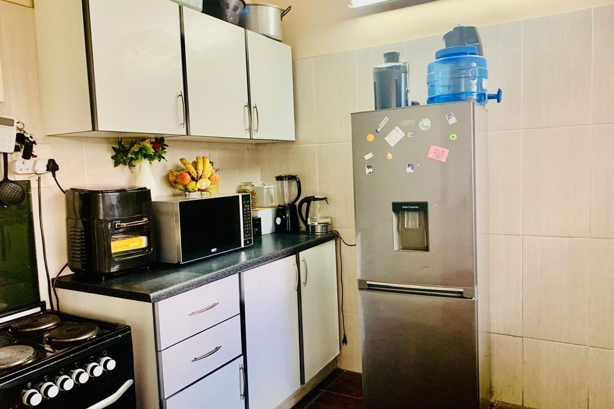 A functional kitchen featuring built-in cabinetry, laminate countertops, and tiled wall finishes, providing a practical workspace for daily meal preparation.