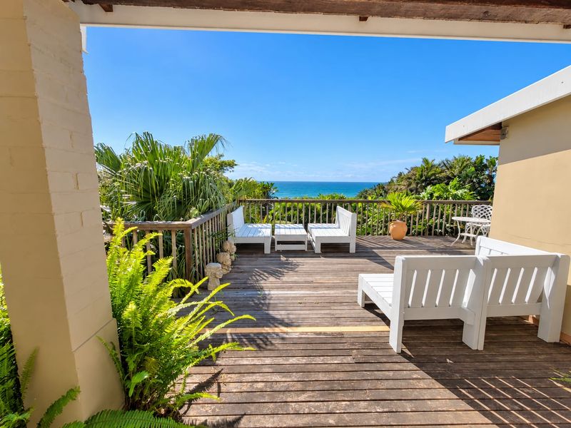 An elevated timber deck patio featuring a balustrade and expansive ocean views, providing a pleasant outdoor entertainment space.