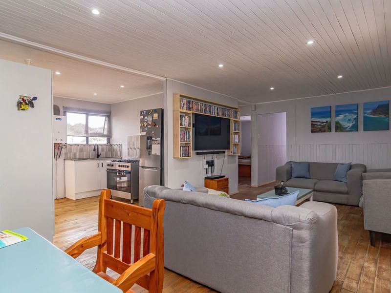 Open-plan living area featuring timber flooring, recessed lighting, and a functional kitchen with built-in cabinetry and gas stove.